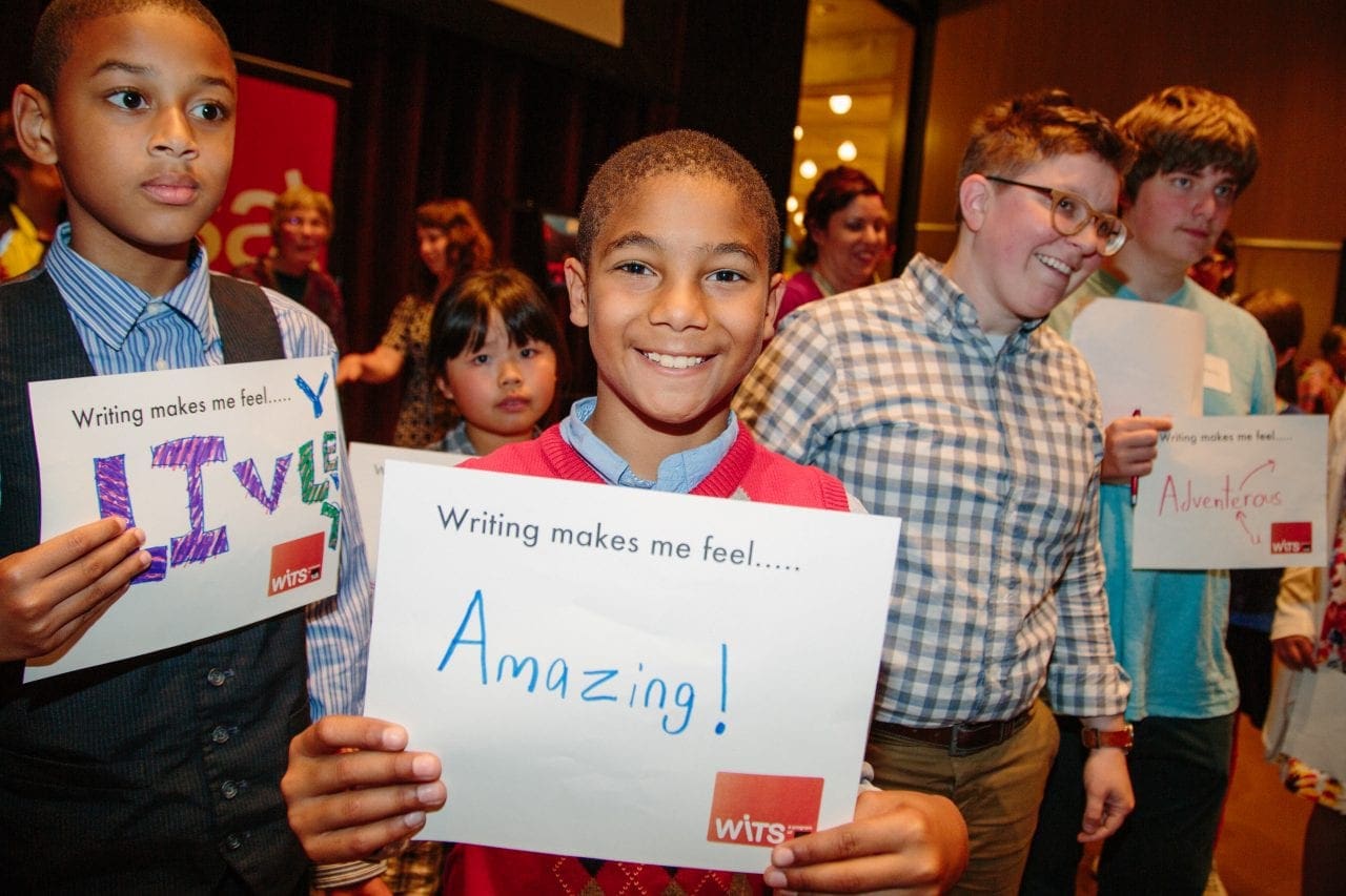 Two young boys at a reading hold up signs that say, 