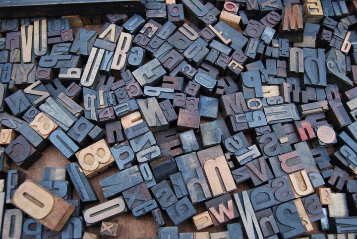 A collection of letterpress letter stamps, all facing upwards, in different shapes and sizes.