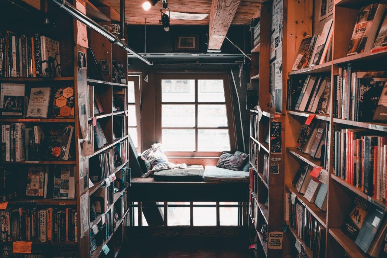 A cozy window shot at Left Bank Books, with a reading nook in a window amidst shelves of books.